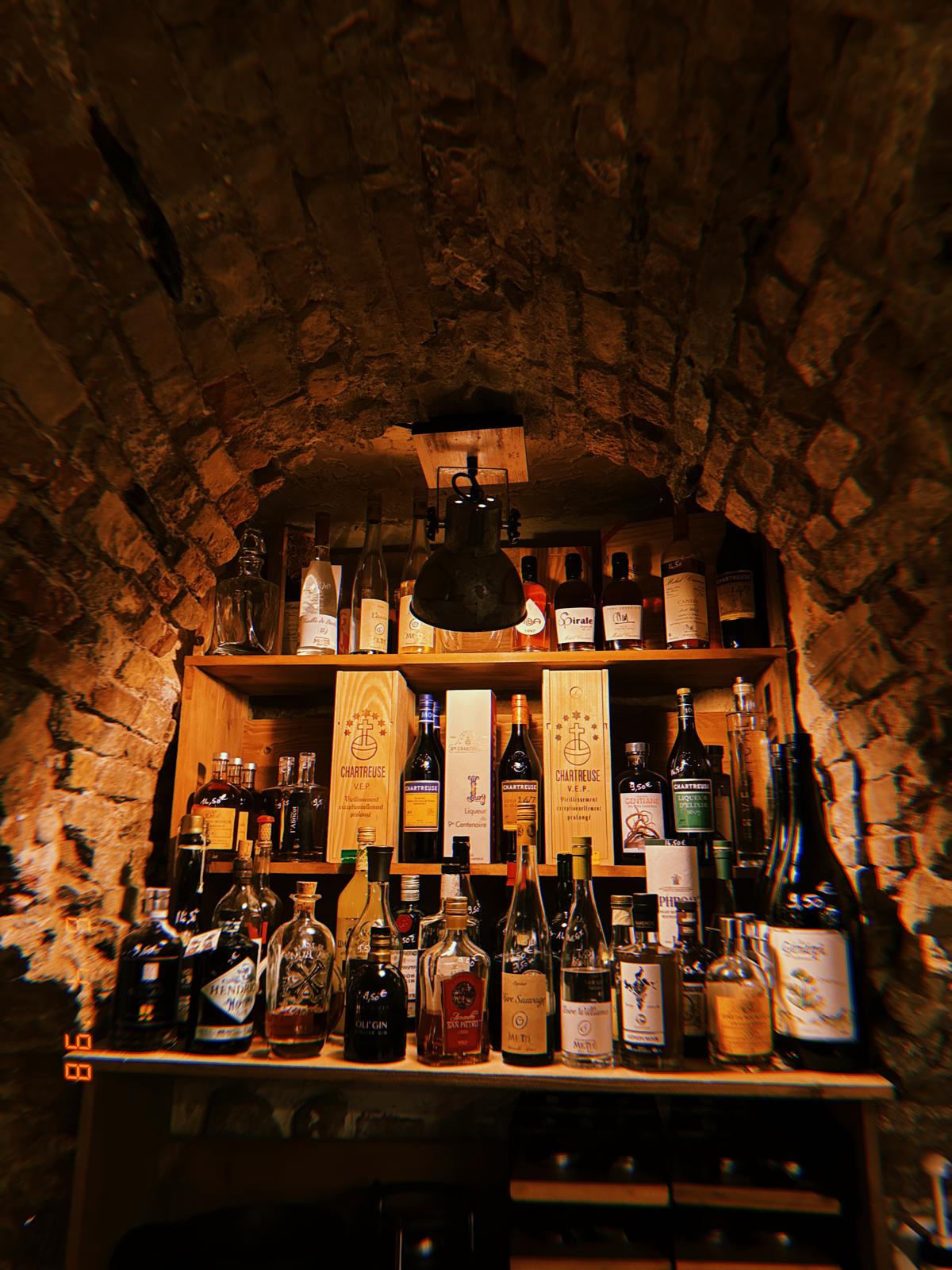 Arche de pierre de la cave et son étagère de digestifs, dont les Chartreuse V.E.P.