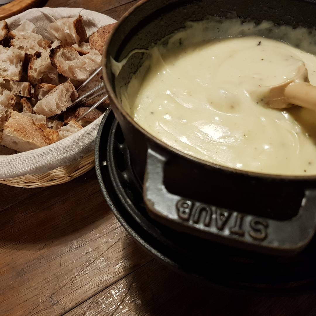 Caquelon Staub de fondue au Comté et Morbier sur son réchaud, panier de pain maison coupé à côté