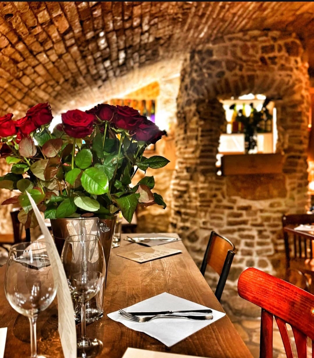 Salle voûtée en brique de La Cave du Fromager, table dressée et bouquet de roses rouges