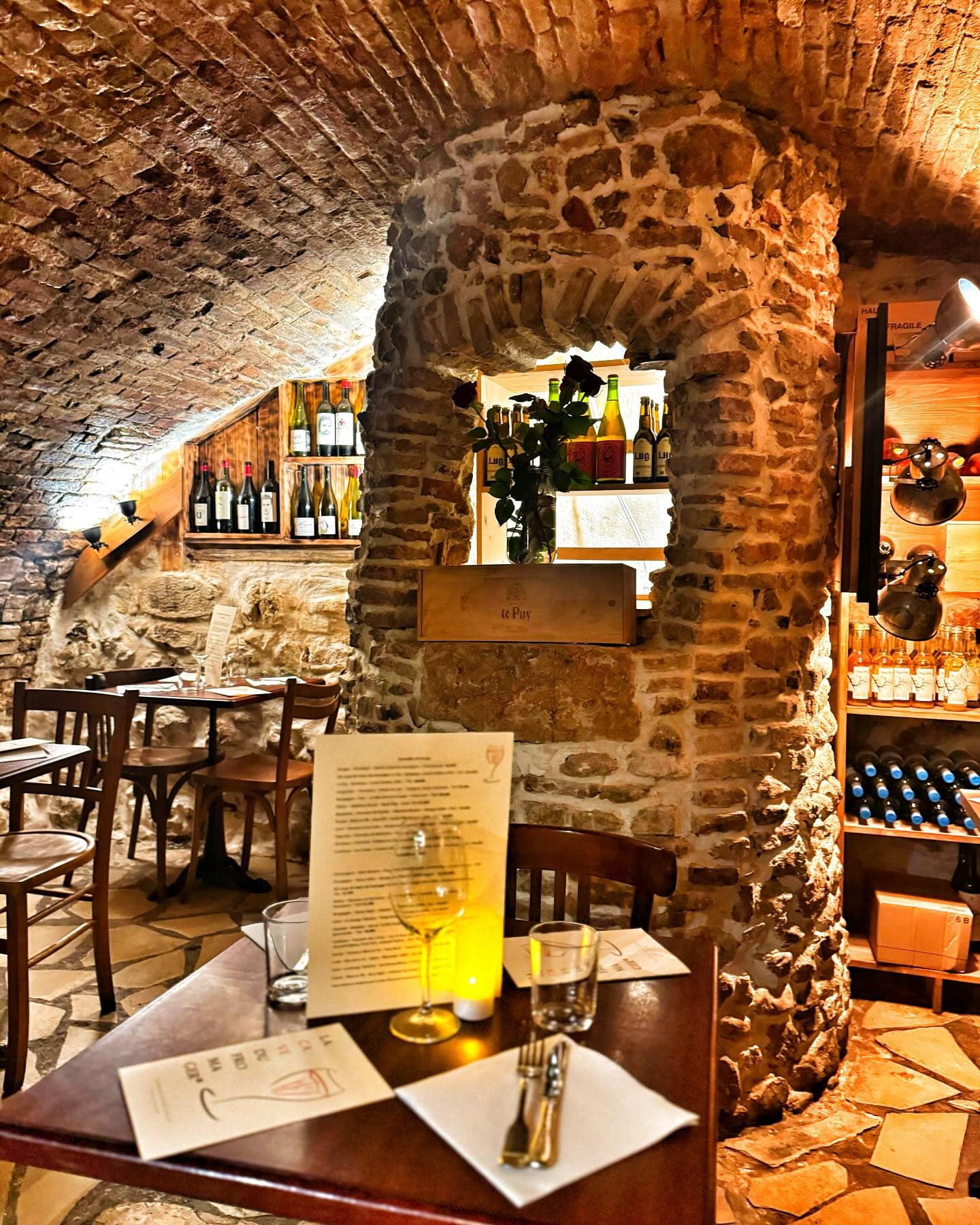 Table dressée pour deux sous une arche de pierre, la carte posée dessus